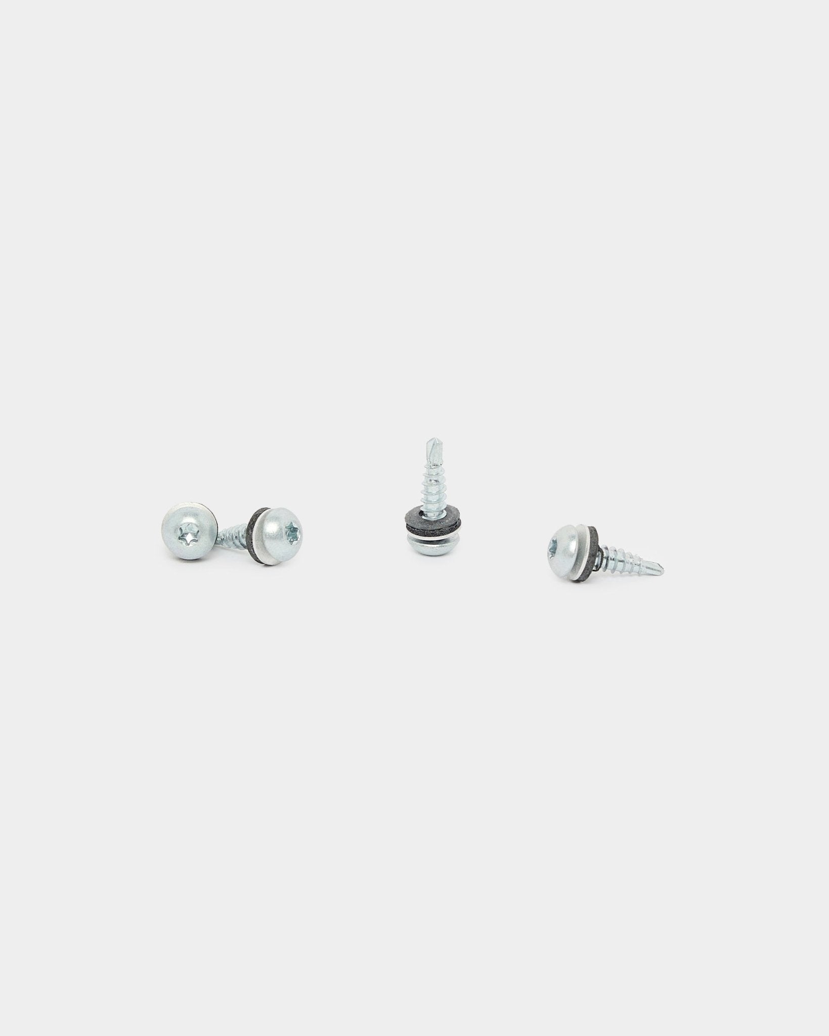 Trzy wkręty montażowe WoodUpp Backside Screws (4.8x19, podkładka Ø10, TX20), używane do montażu Panel akustyczny, ułożone w różnych kierunkach na białym tle.